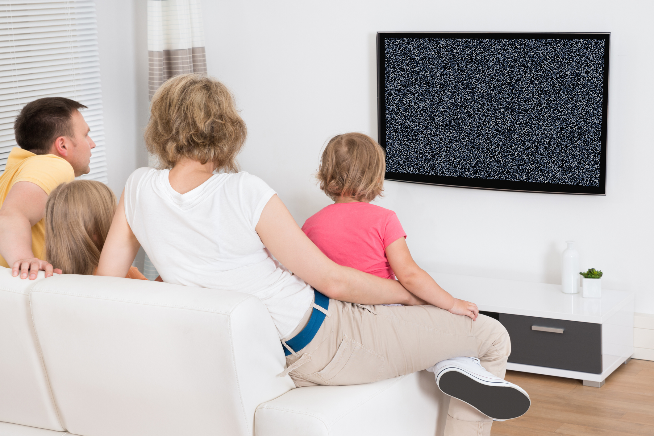 Тревога по телевизору. Семья у телевизора. Семья на диване перед телевизором. Семья перед телевизором с пультом. Семья сидит перед телевизором.